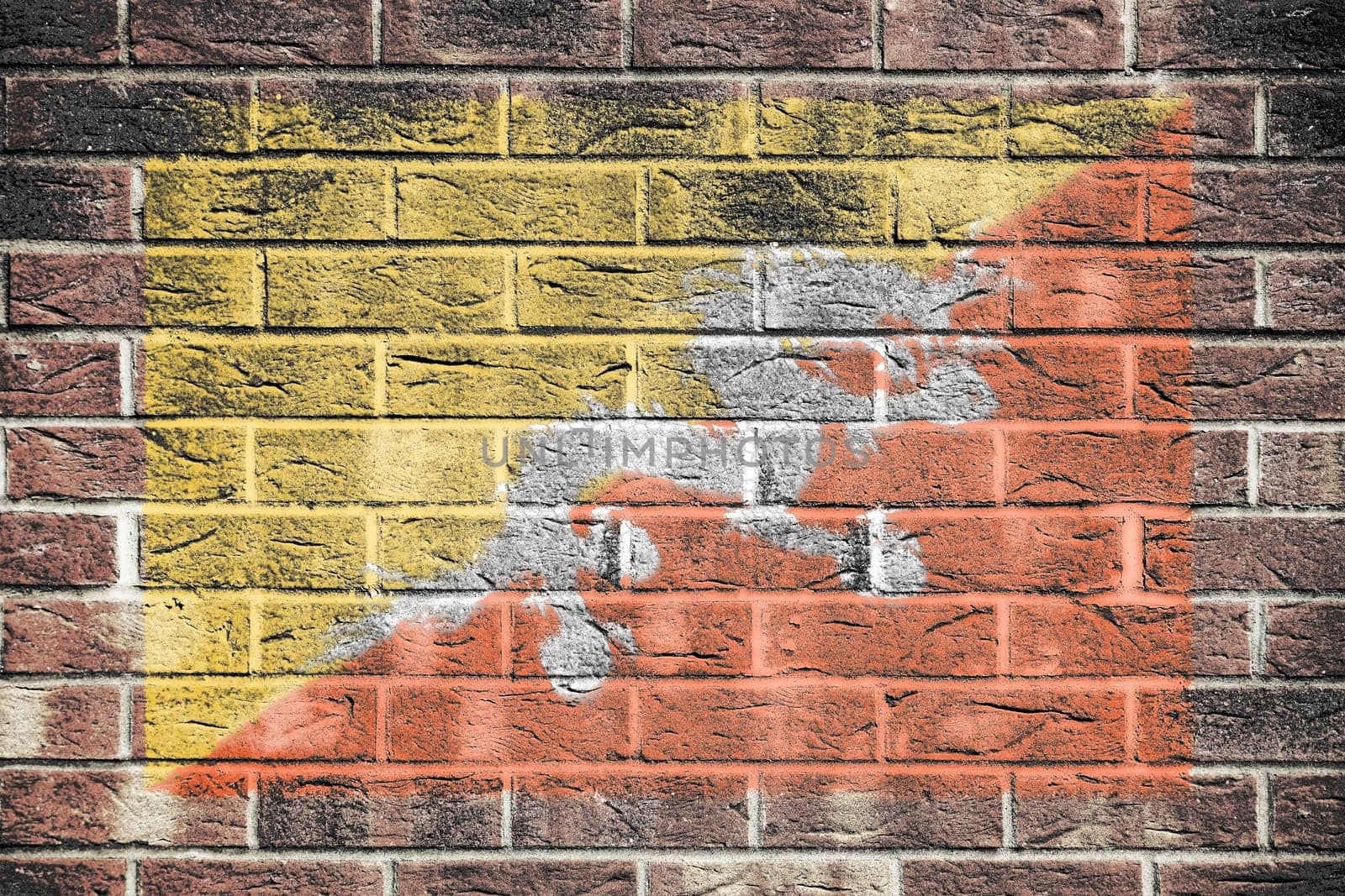 A Bhutan flag on a brick wall background yellow orange diagonal Druk Thander Dragon