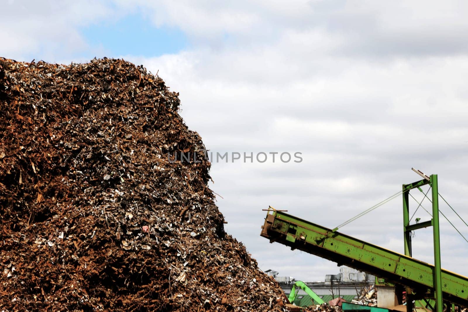 A pile of scrap metal at a junkyard against an overcast sky. Scrap metal and iron.
