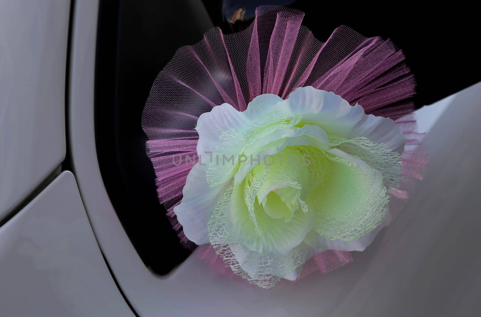 Decorative,wedding flower attached to the bride and groom's car door. Orange, green artificial flower.