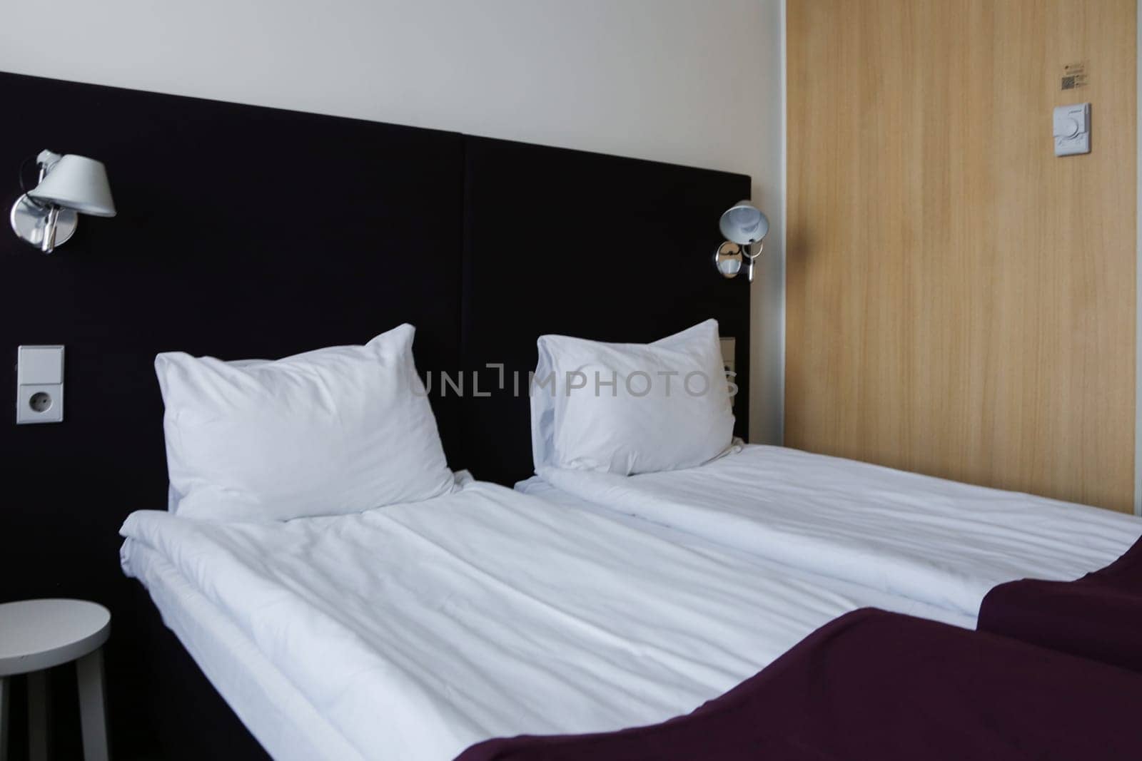 A cozy hotel interior of two beds made up with new, clean linens, a white pillow, a white sheet. Cozy bedroom in a hotel.