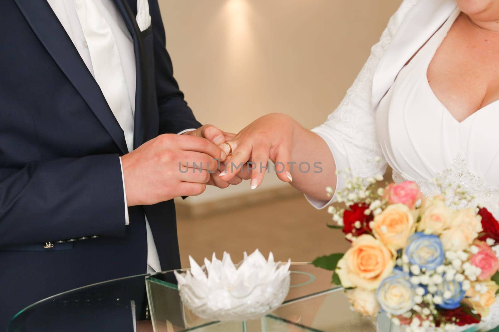 The groom puts the wedding wedding ring on the bride's ring finger,bridal bouquet,festive entourage.