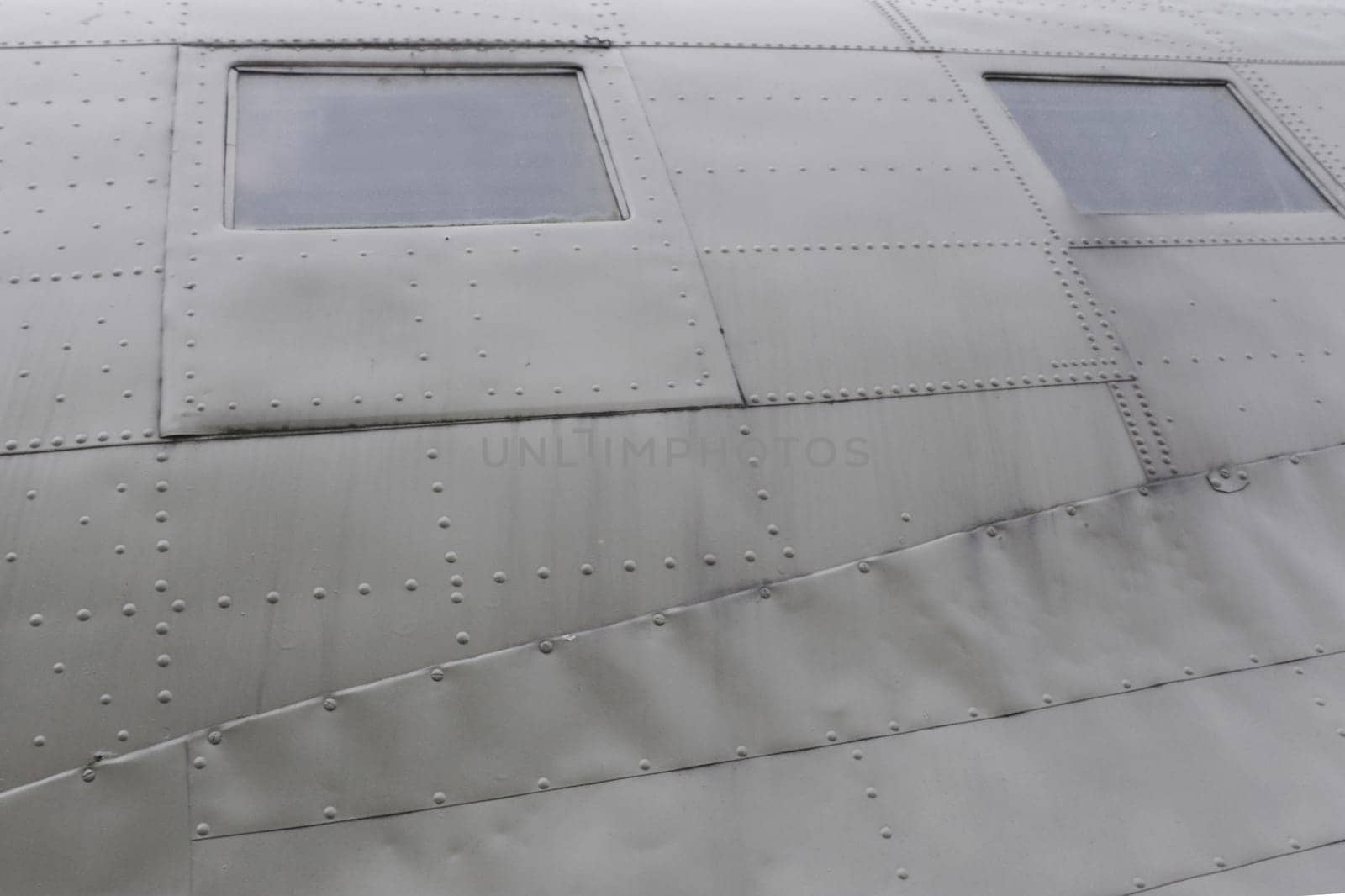 Windows in Airplane Fuselage. Two square fuselage windows on the side of an old green transport aircraft.