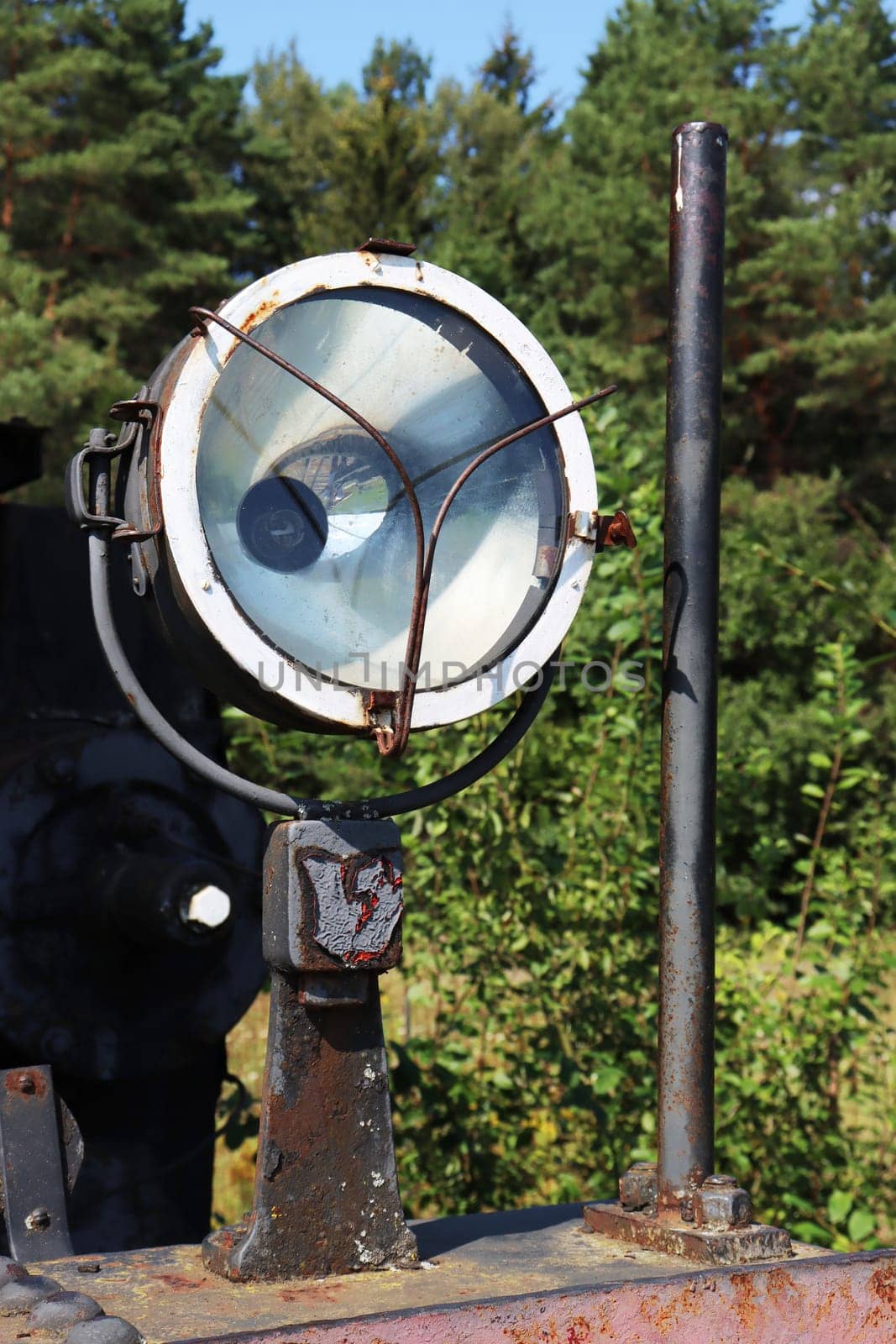 Vertical photo of a spotlight lamp from an old, abandoned steam locomotive.