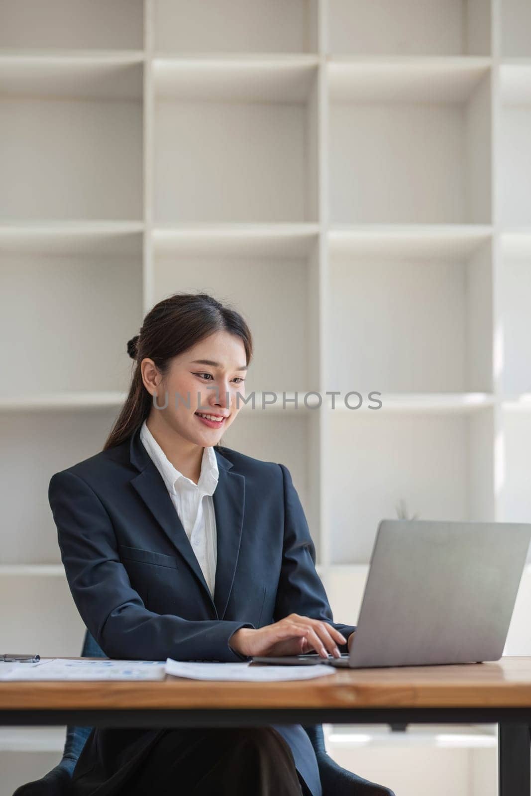 Asian businesswoman use laptop computer in office The Internal Revenue Service audit document balance calculation report is being prepared. by wichayada