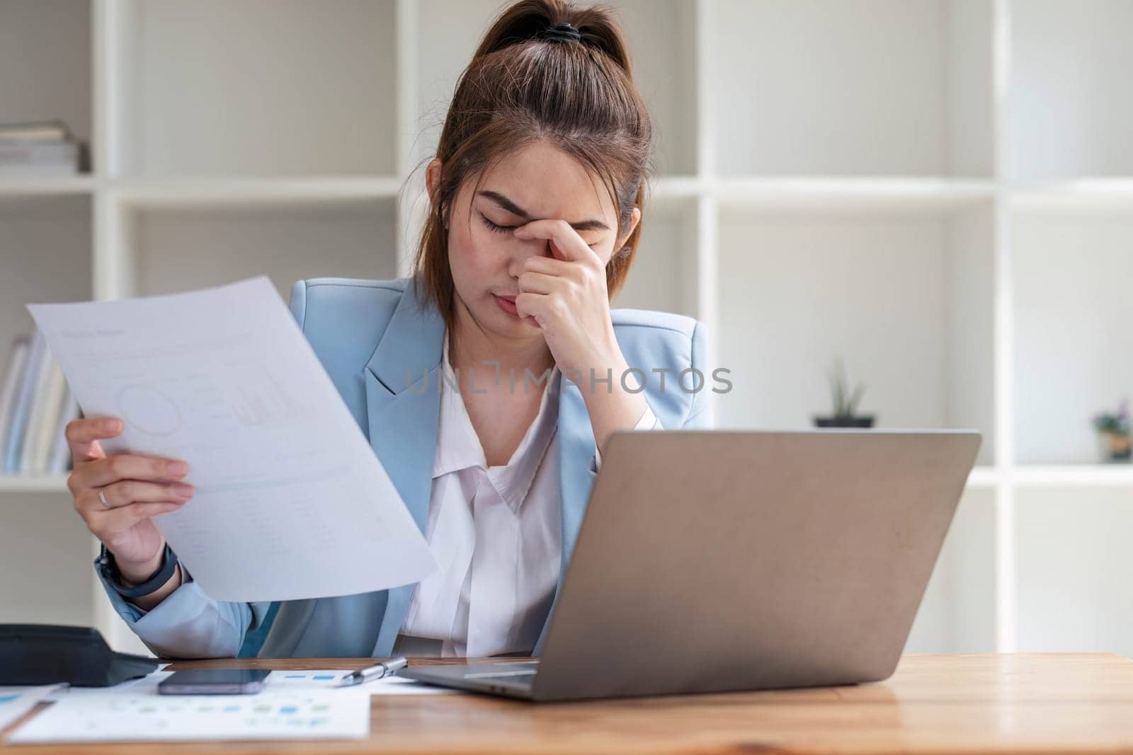 Confused Asian woman thinking hard about how to solve problems online looking at laptop screen. Serious Asian businesswoman worried focused on solving difficult computer at office by wichayada