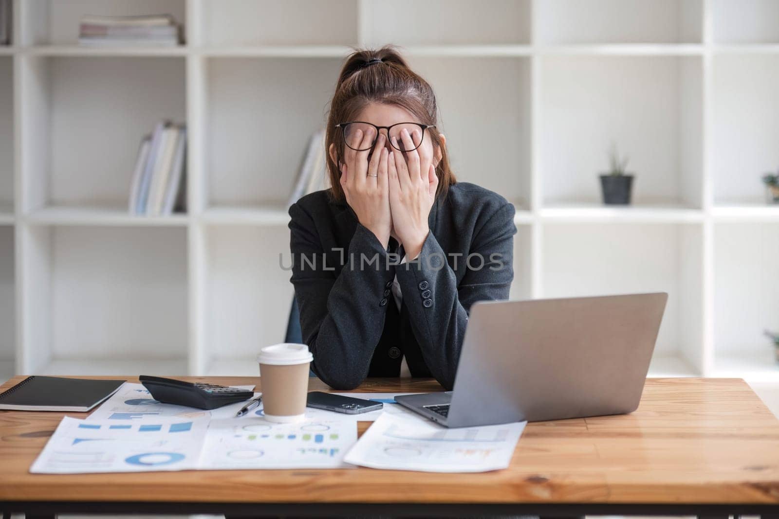 Confused Asian woman thinking hard about how to solve problems online looking at laptop screen. Serious Asian businesswoman worried focused on solving difficult computer at office by wichayada