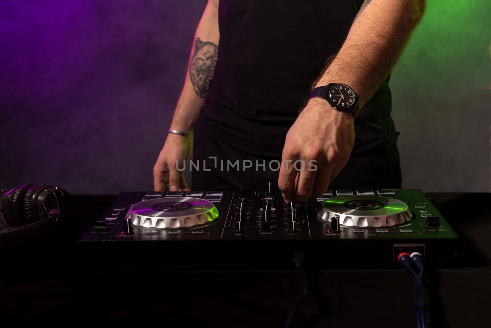 Dj mixing on turntables with color light effects. Soft focus on hand. Close-up. Fun, youth, entertainment and fest concept