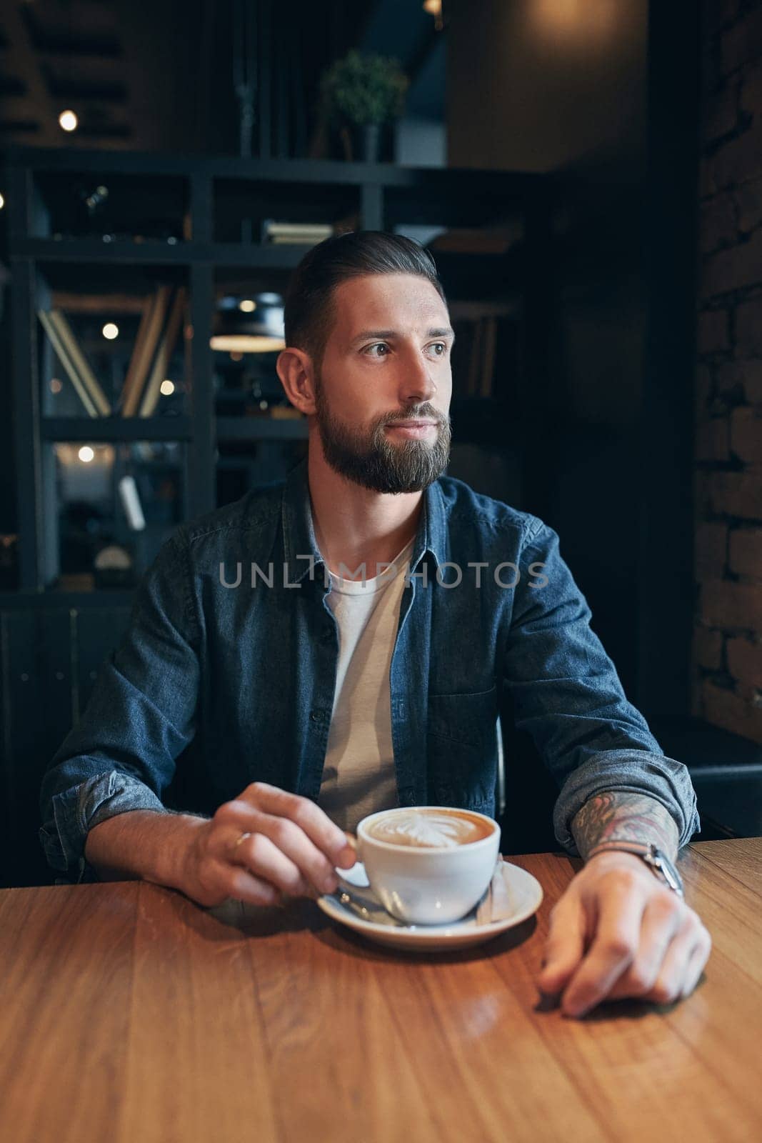 Confident man enjoying a cup of coffee while having work break lunch in indoors cafe looking pensive by nazarovsergey
