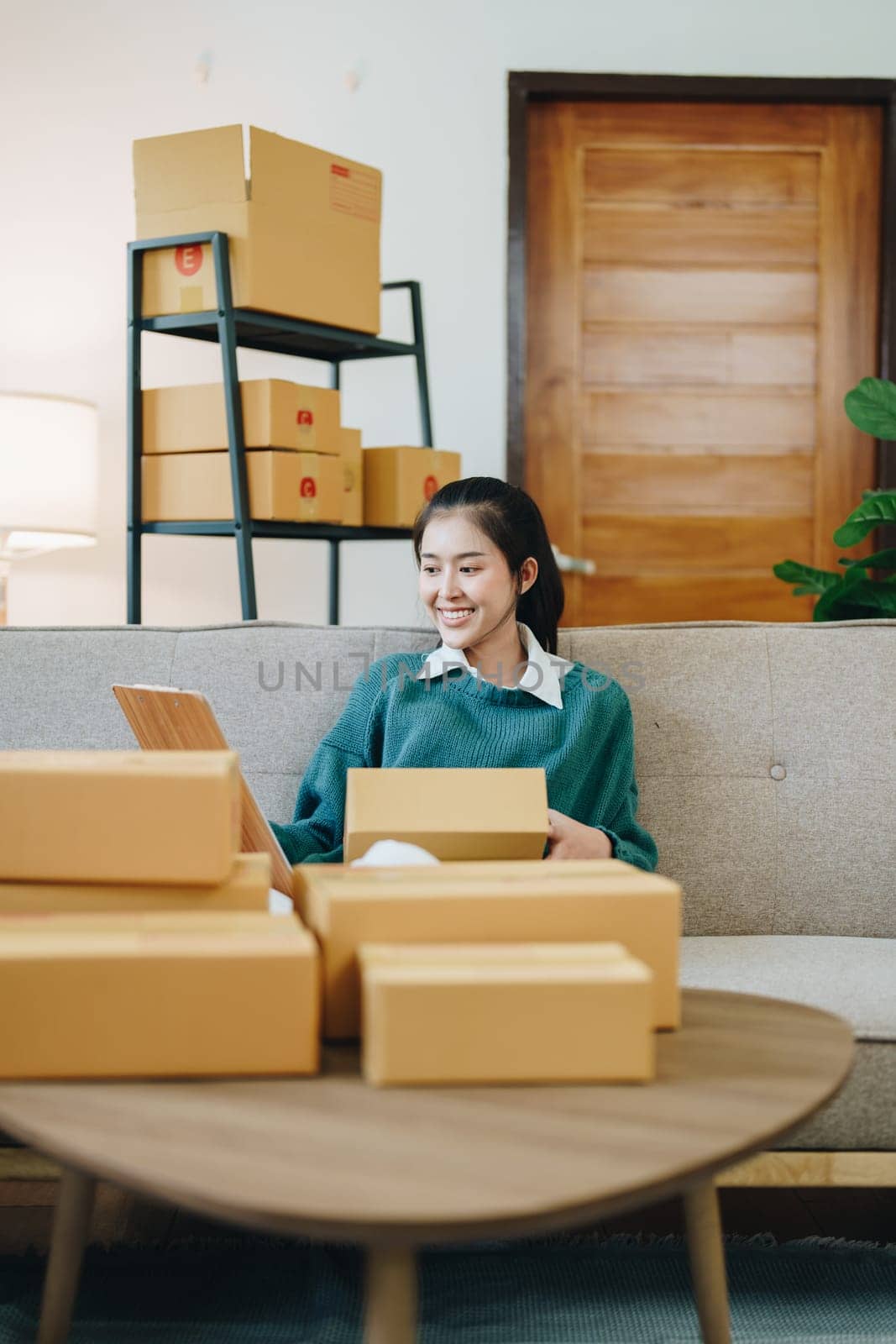 Starting small business entrepreneur of independent Asian female online seller packing products to send to customers and SME delivery concept.