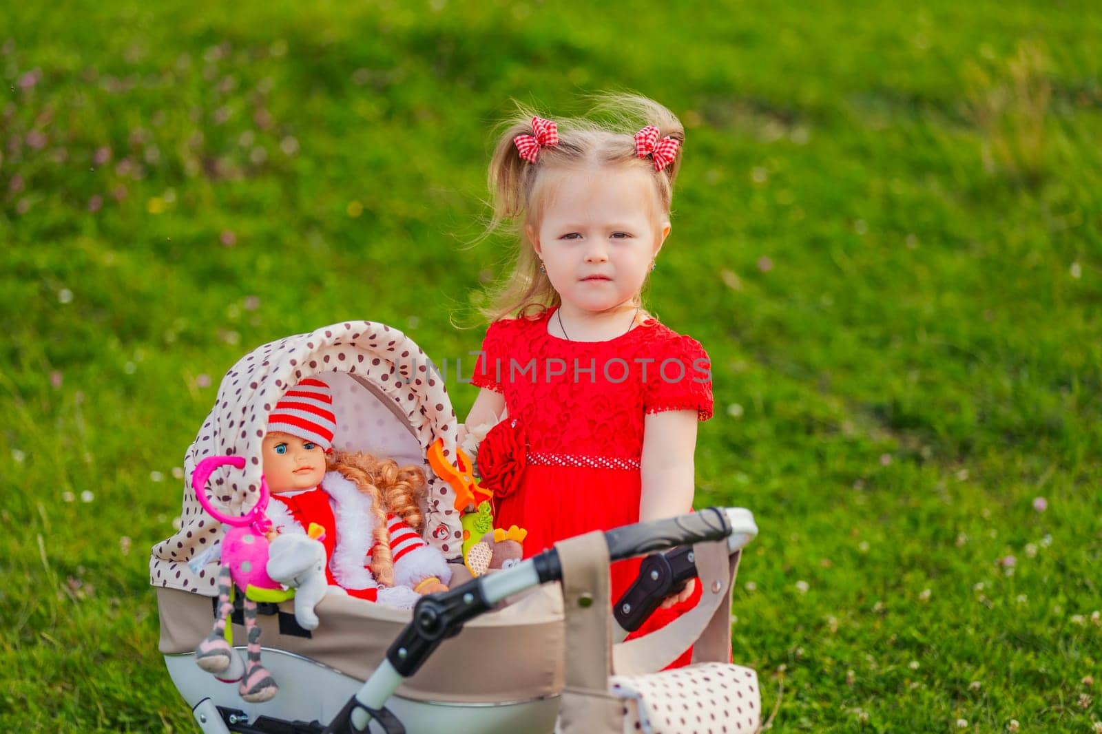 a child with a toy stroller and a doll is playing in nature