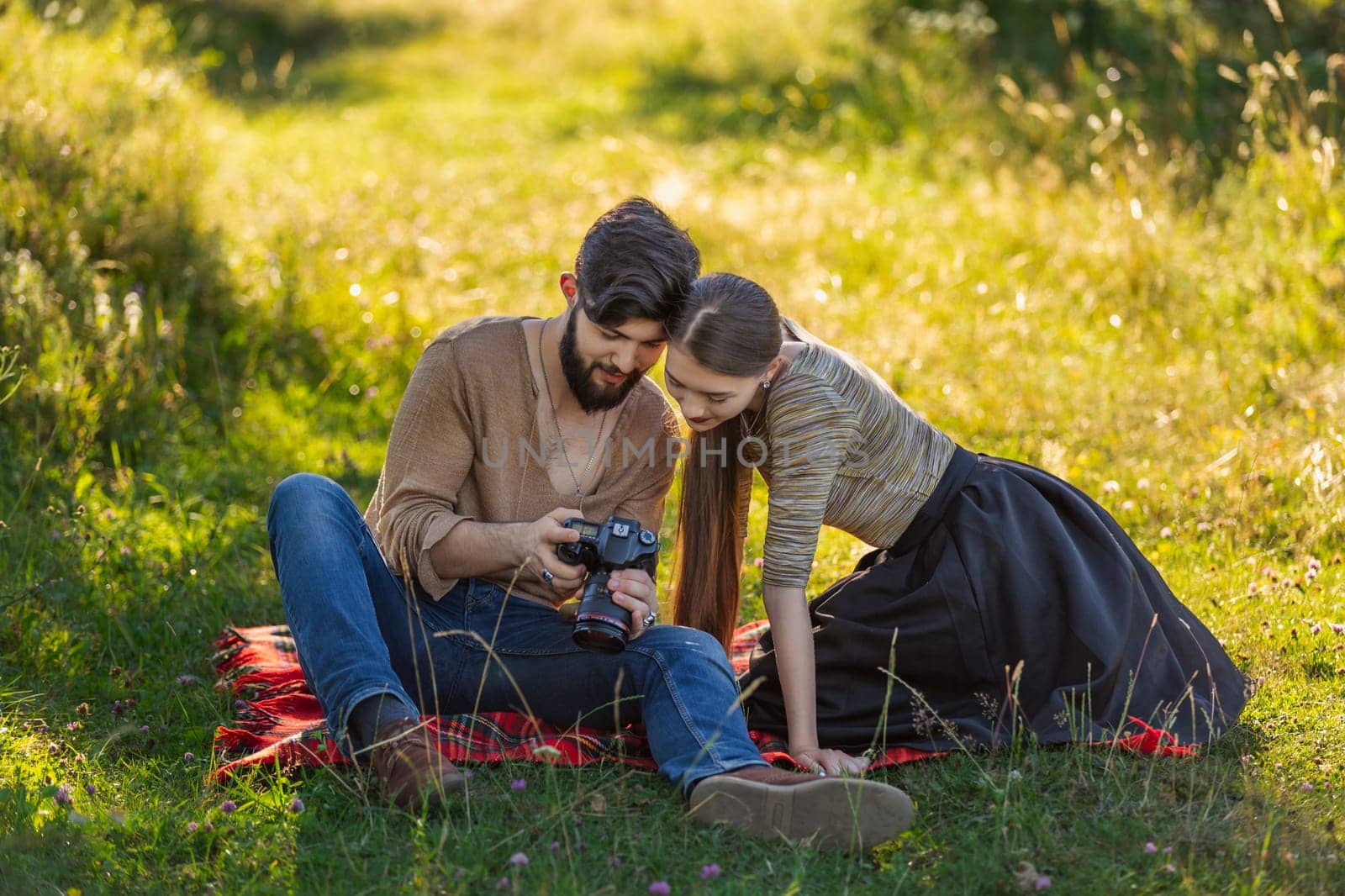 young couple sits in nature and looks at the camera at the resulting picture