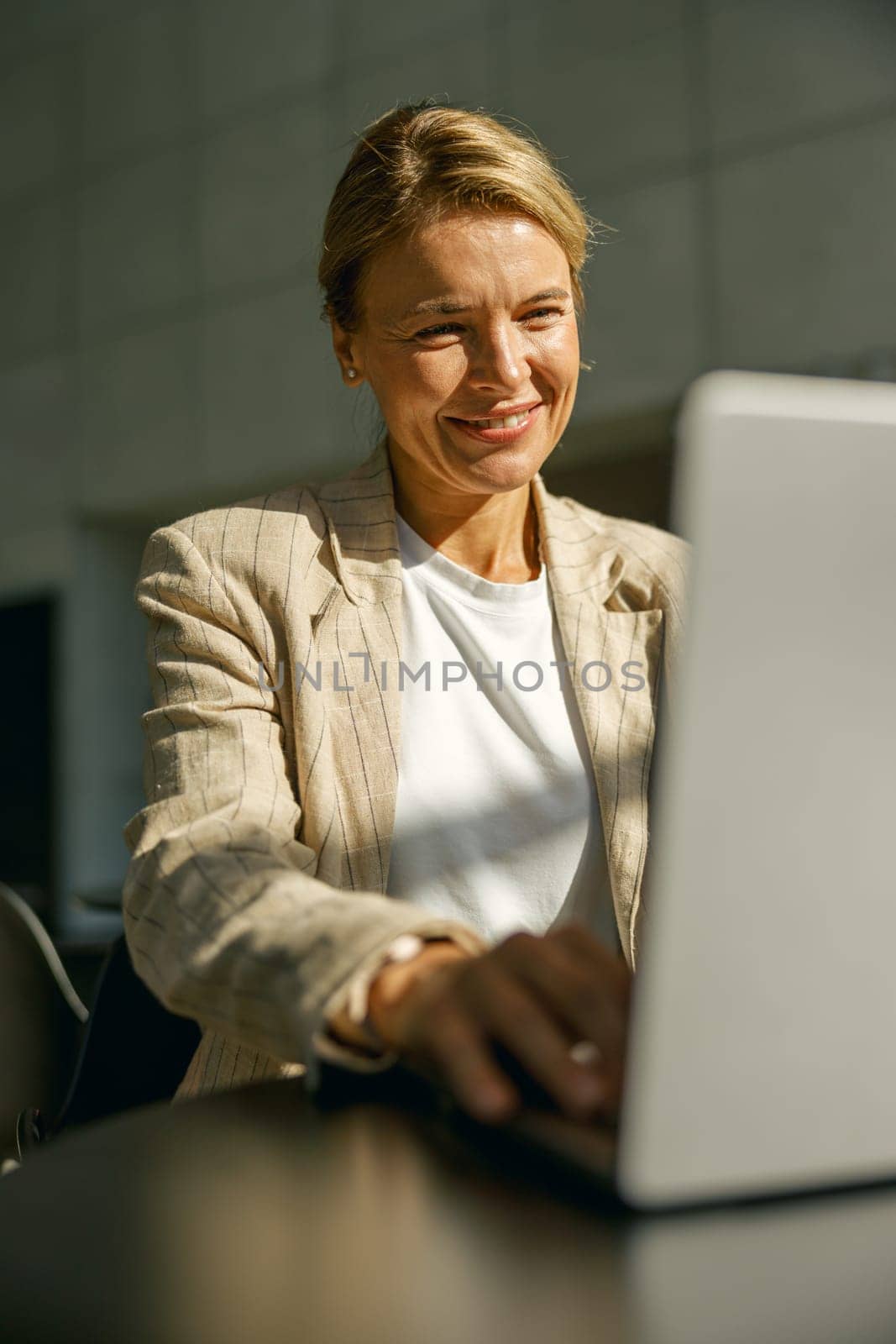 Smiling female sales manager working on laptop while sitting the desk in modern coworking