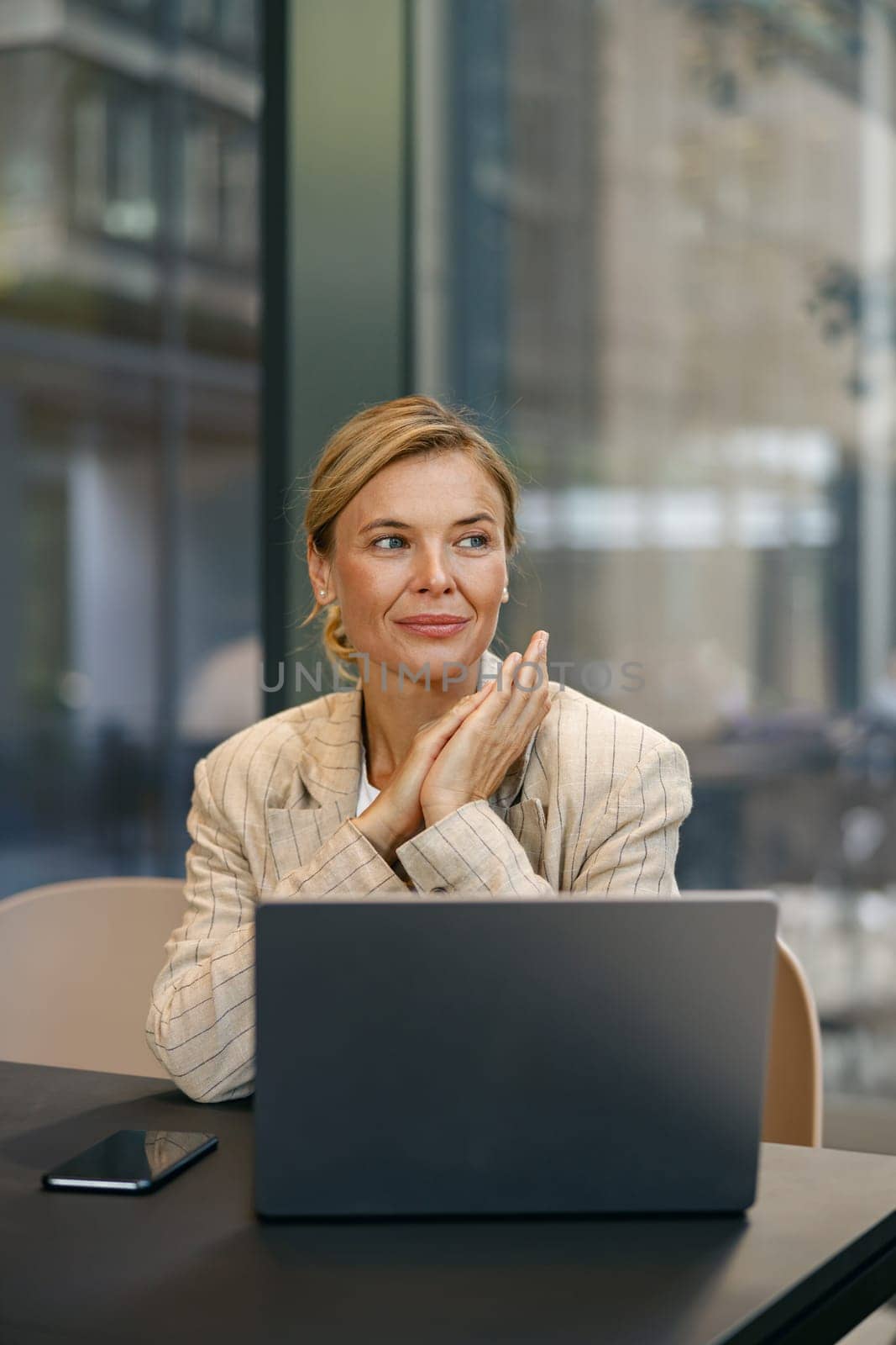 Focused mature woman sales manager working on laptop in modern coworking background