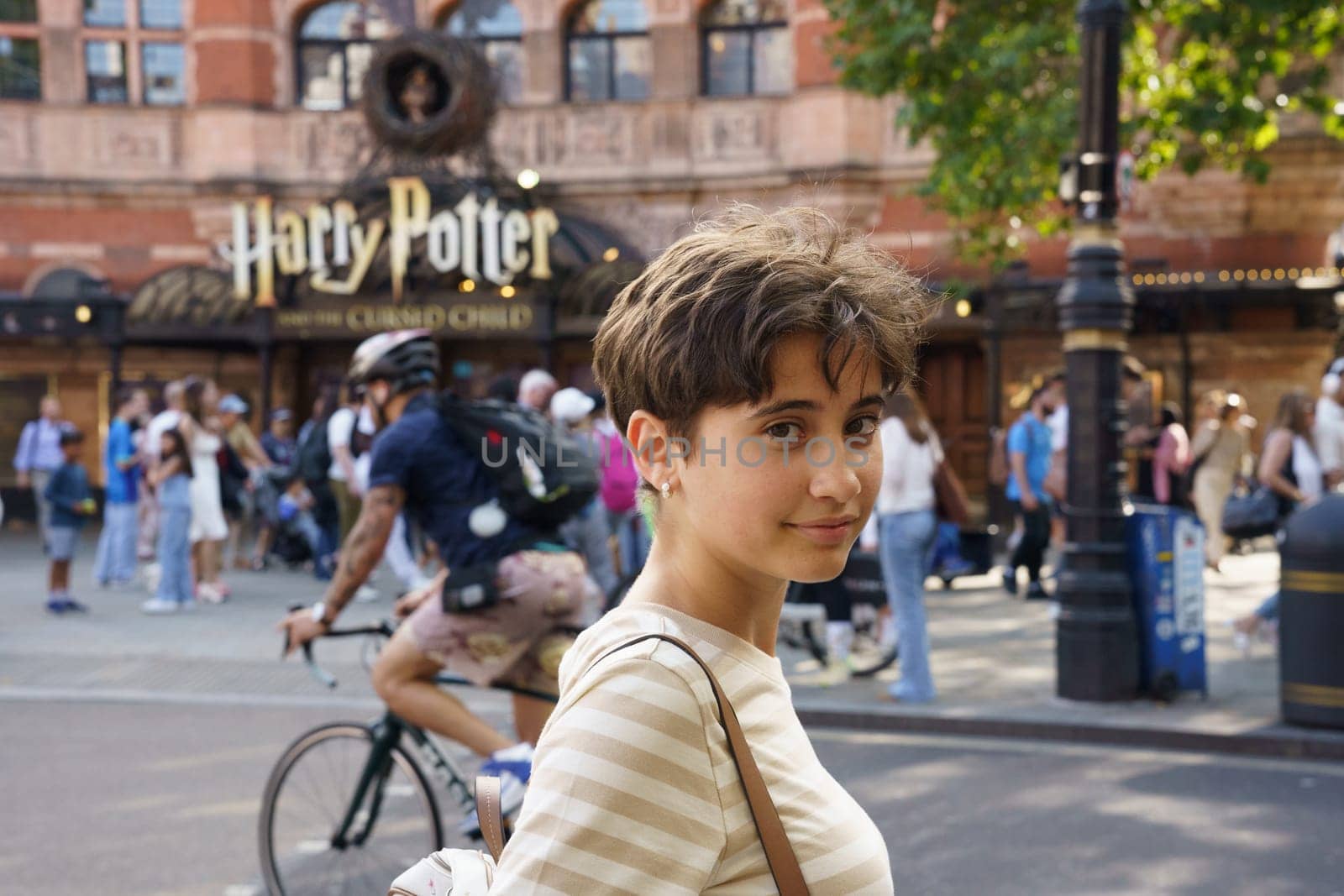 London, United Kingdom, july 18th 2024. Teenage girl in front of the facade of The Palace theatre in London. Play with the musical play Harry Potter and the Cursed Child.