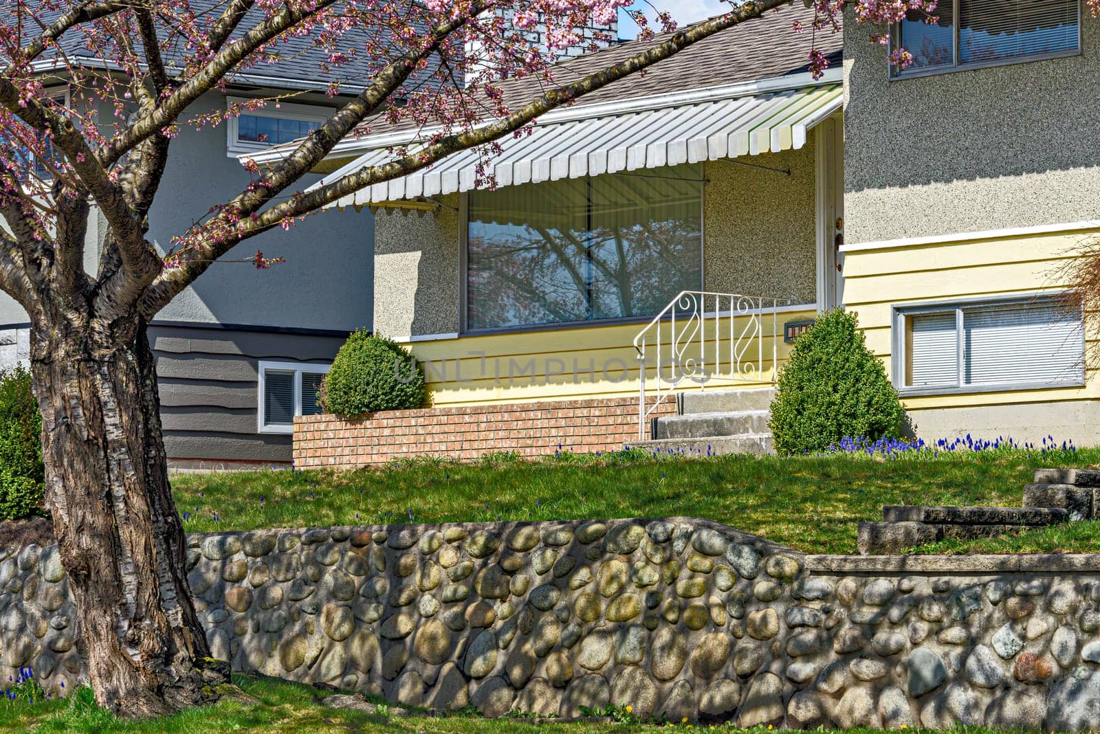 Entrance of the family house under the canopy with front lawn on the land terrace.