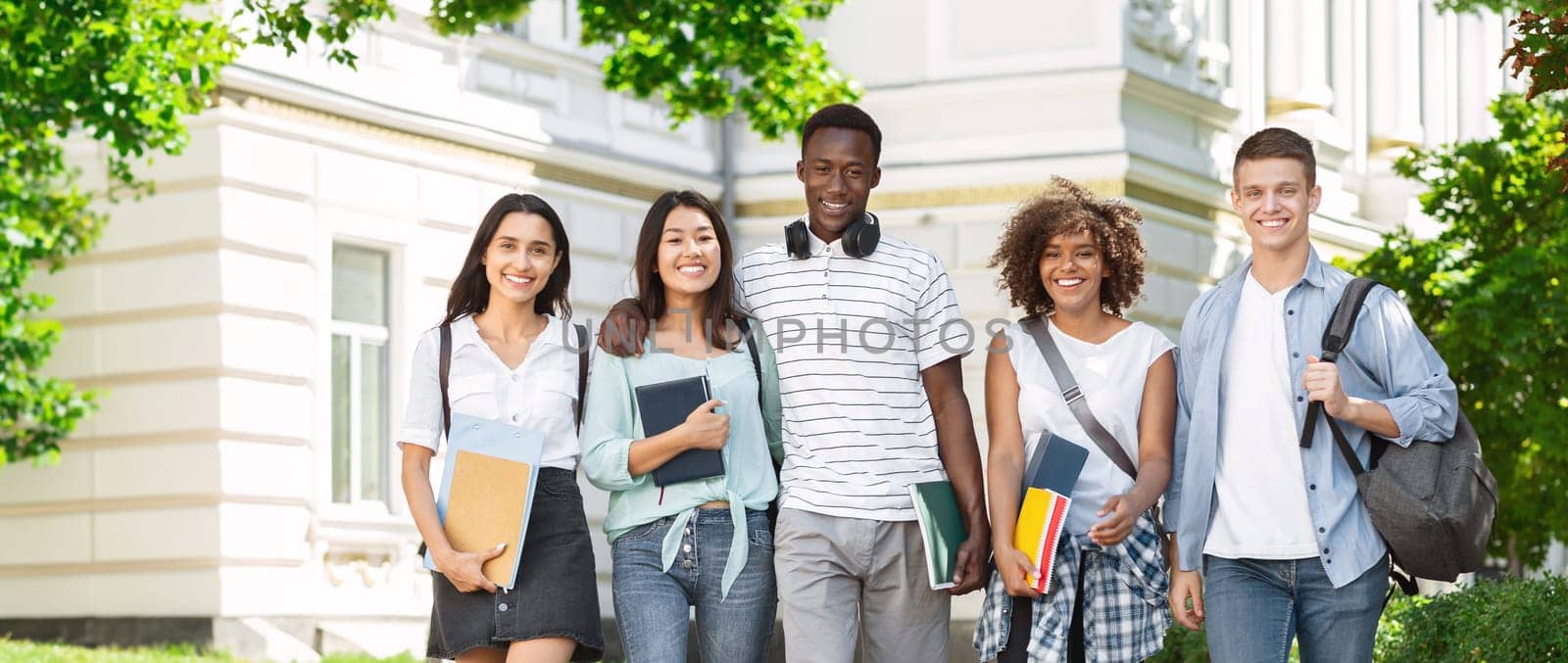 Happy Interracial College Friends Walking In Campus And Smiling To Camera, Enjoying Spending Time Together Outdoors, Free Space