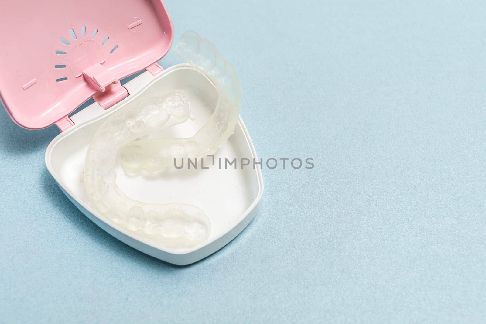 Dirty Teeth Dental Night Guards in Box, White Pink Container. Blue Background. Copy Space For Text. Clear Retainer. Oral Hygiene, Cleaner. Horizontal Plane. High quality photo