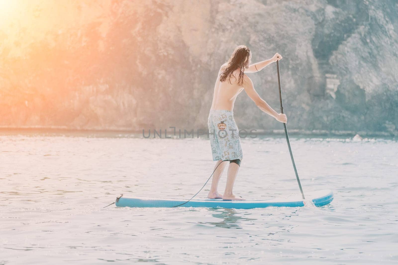 Man Sea Sup. Strong athletic man learns to paddle sup standing on board in open sea ocean on sunny day. Summer holiday vacation and travel concept. Aerial view. Slow motion.