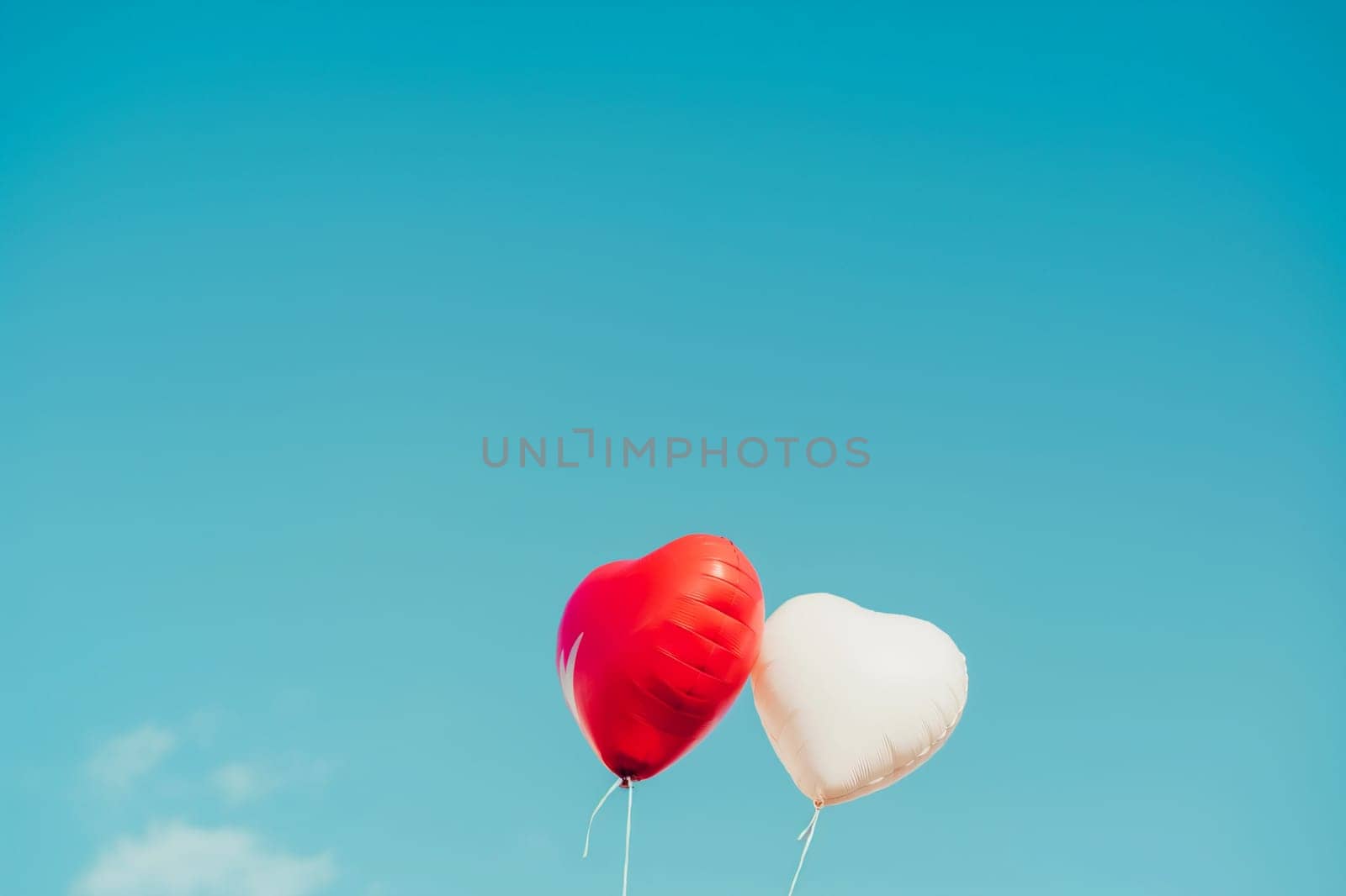 Heart balloons floating in the blue sky&#58; red and white pair symbolizing love and romance