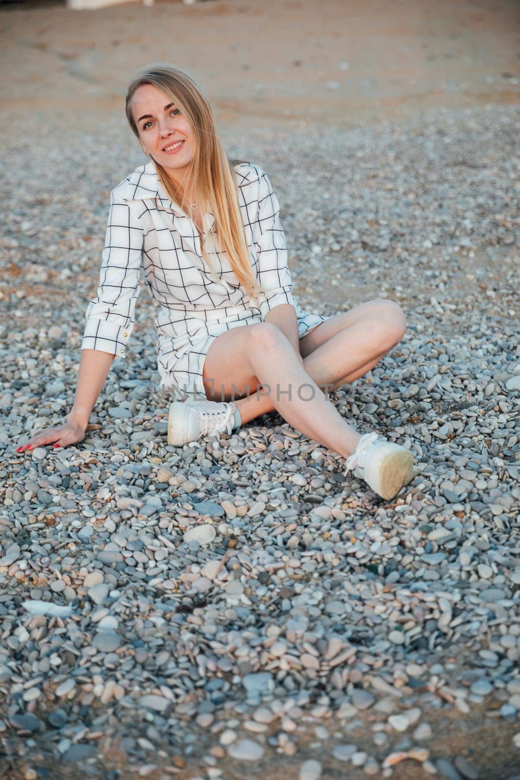 beautiful woman sitting on pebbles on the shore