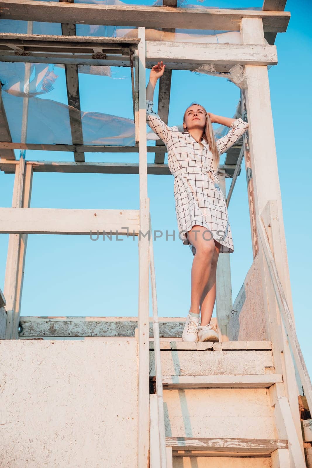 a beautiful blonde stands on the wooden stairs of the house