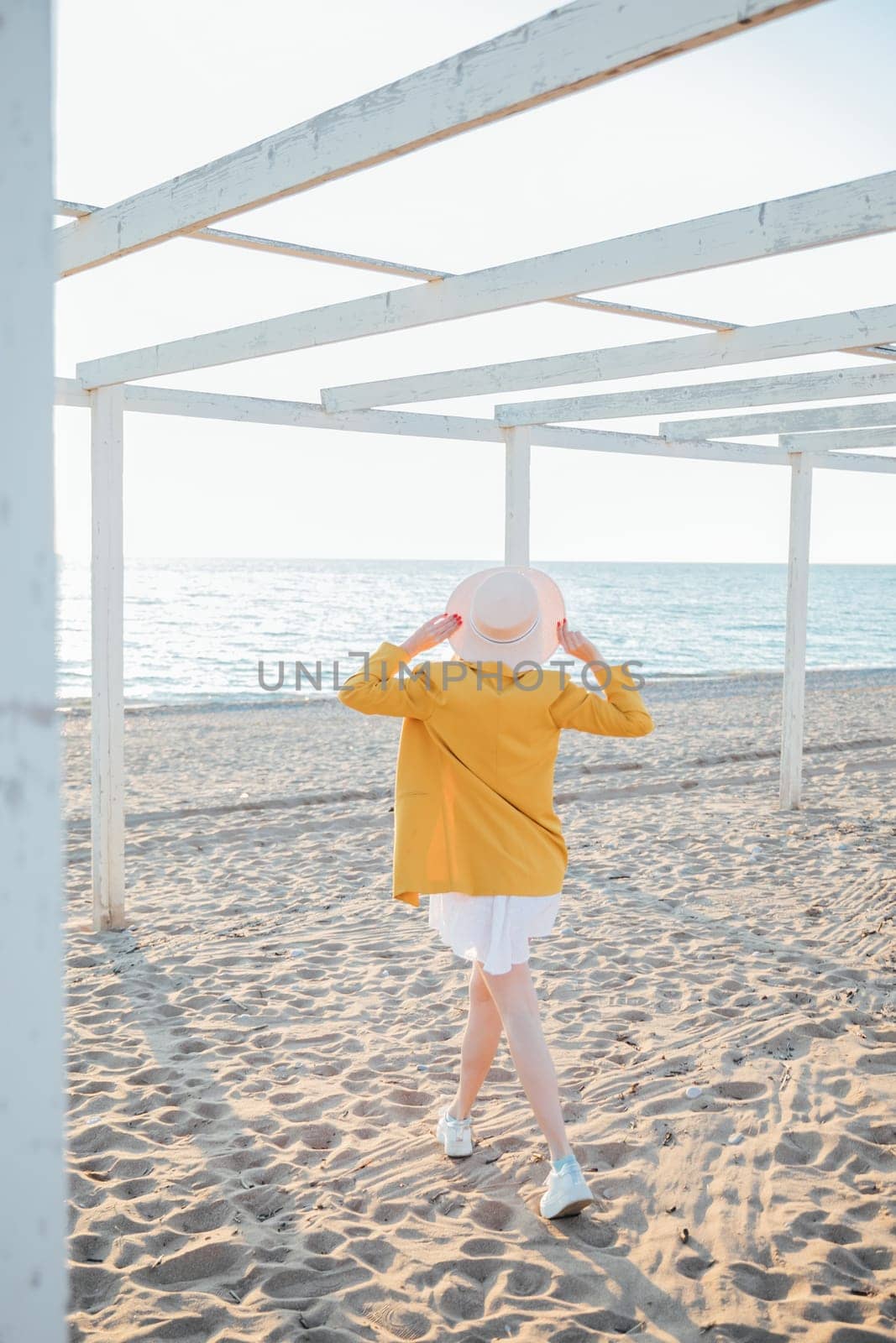 woman in a hat walks to the sea on the sand