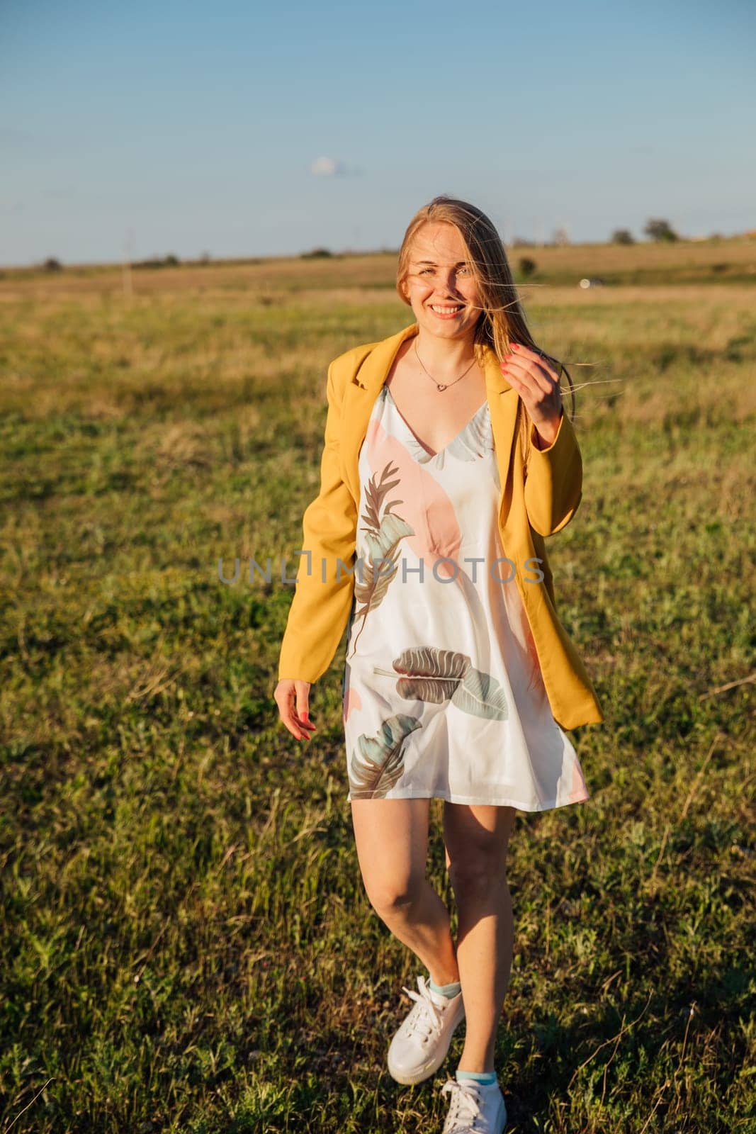 a blonde woman in yellow clothes in nature green meadow