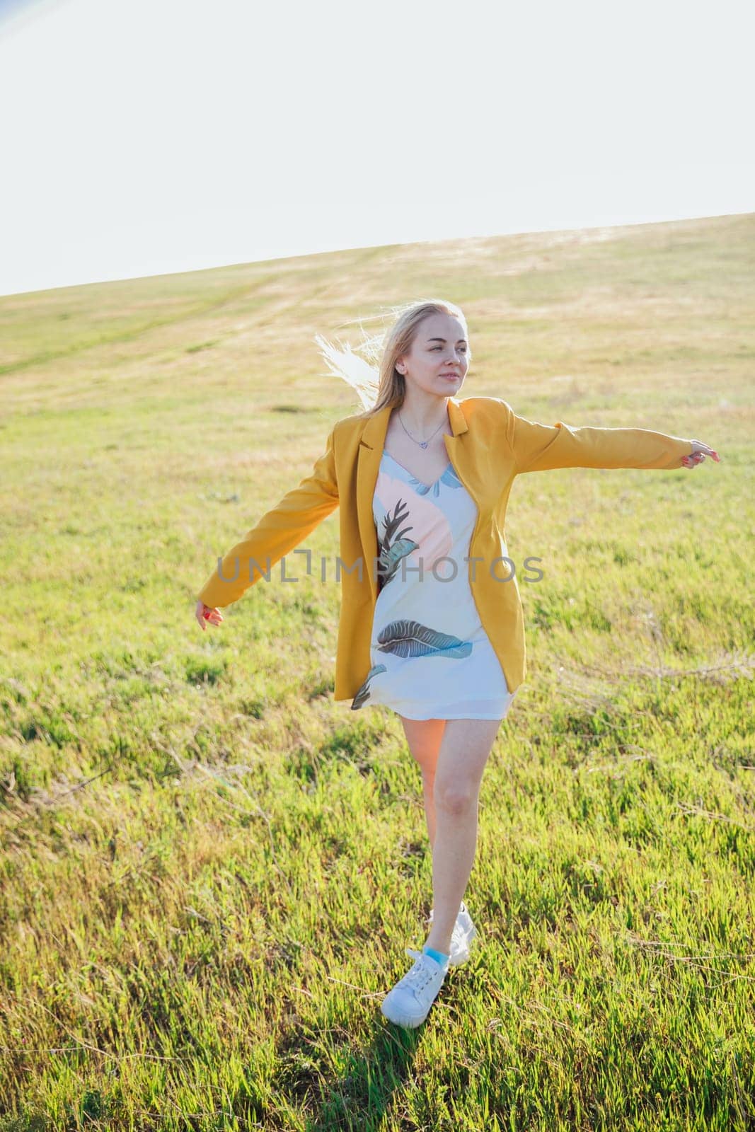 a blonde woman in yellow clothes in nature green meadow