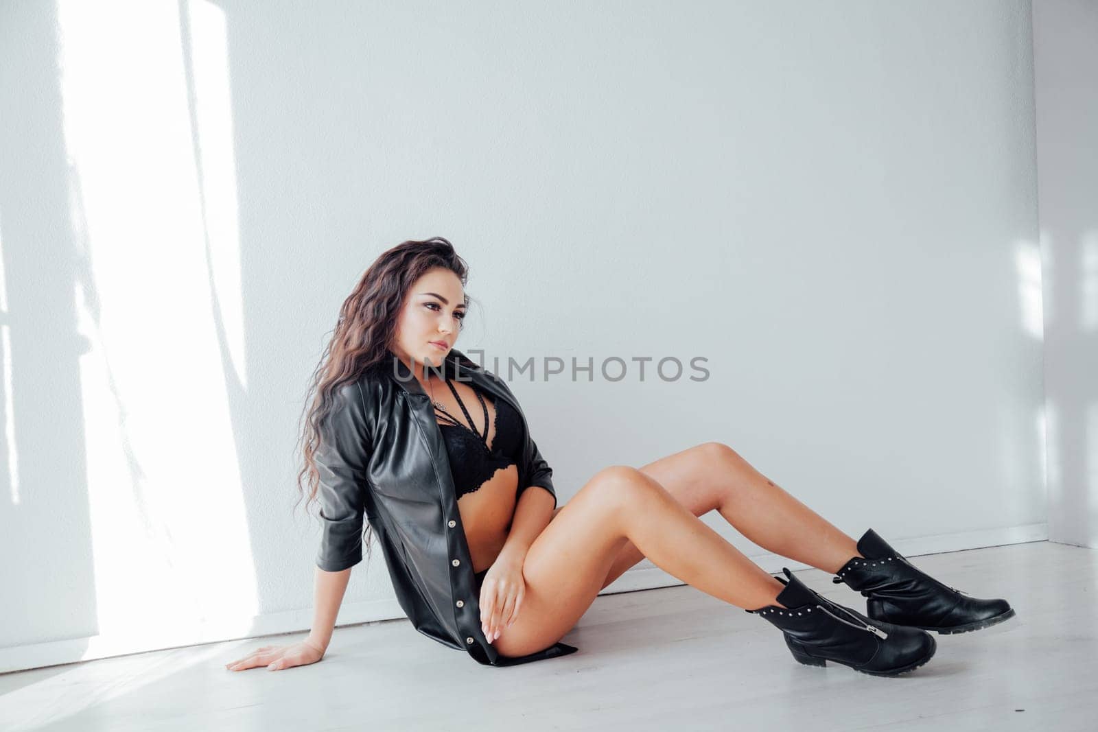 a brunette in black underwear and clothes sits on the floor in the room