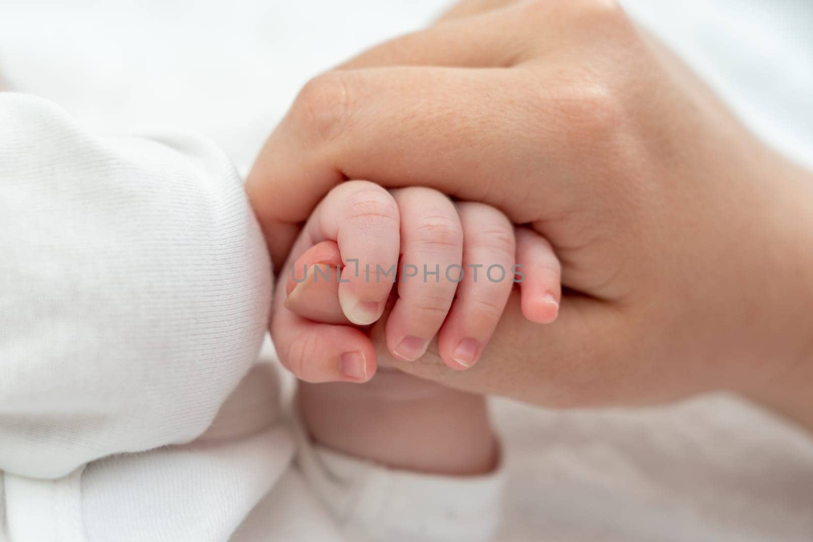 Newborn's delicate grip on mother's thumb exudes trust. Concept of pure maternal connection by Mariakray