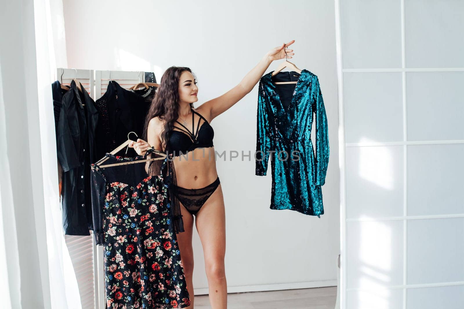 woman in black underwear stands with clothes in the wardrobe of a clothing store
