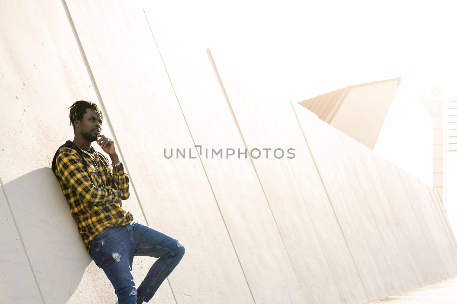 young black man leaning against a modern concrete structure at sunset, lifestyle concept