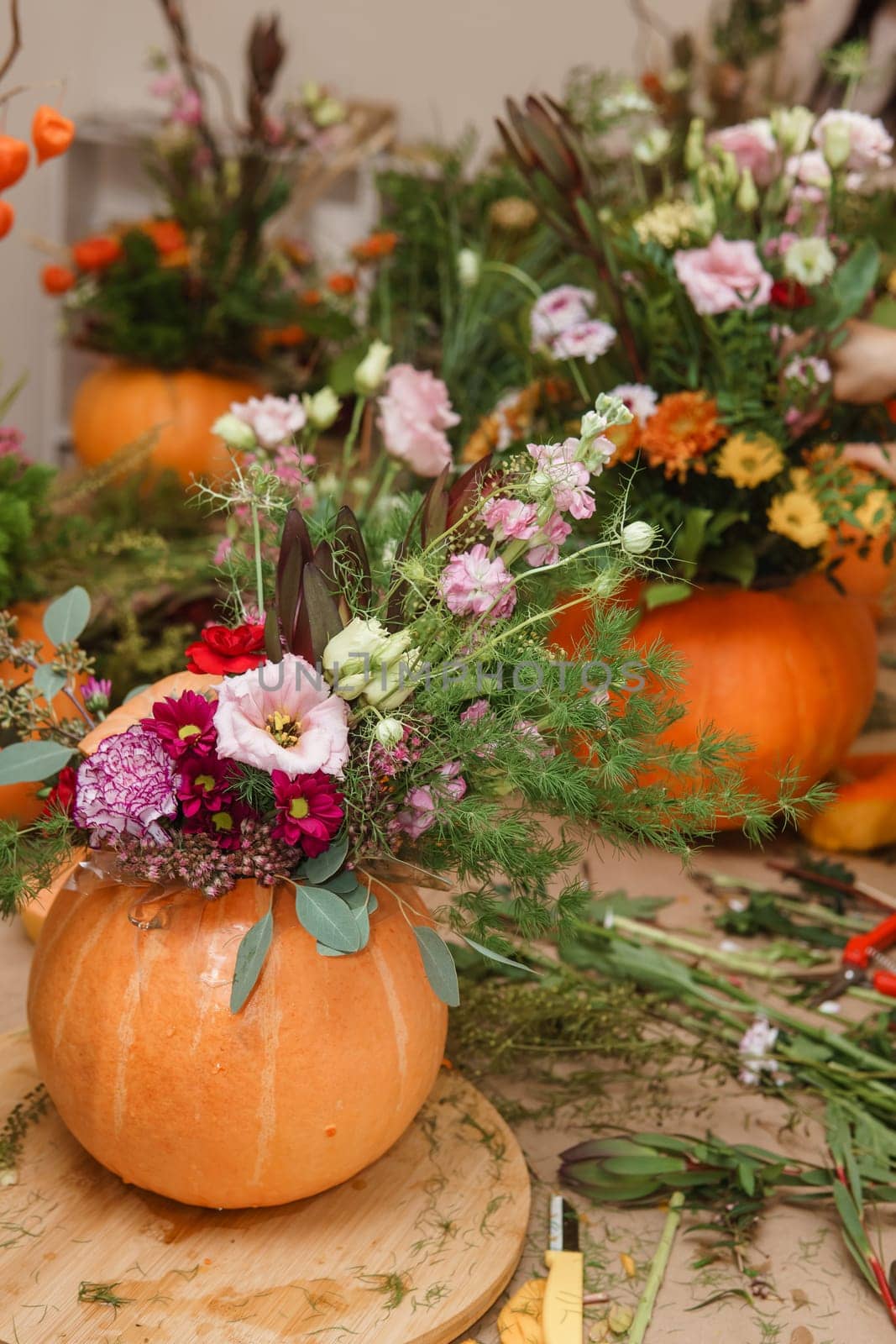 Flower arrangement in a pumpkin, autumn interior decor. Creating handmade autumn decor