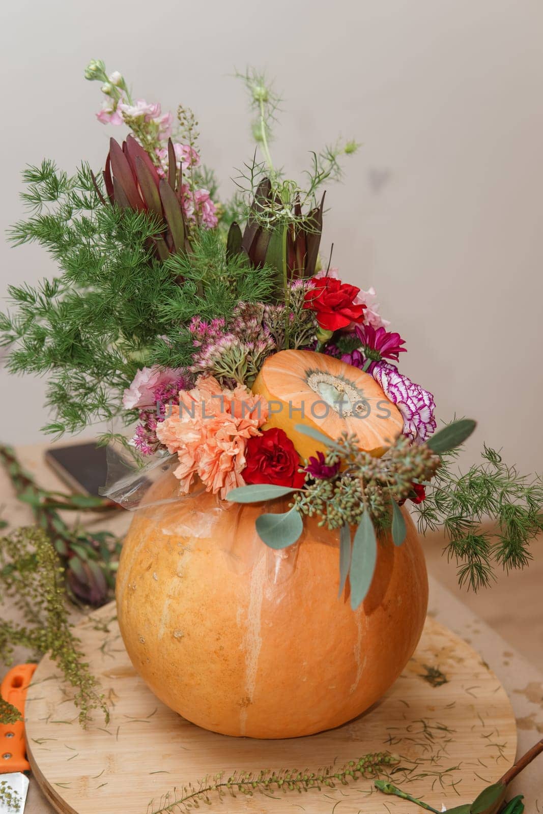 Flower arrangement in a pumpkin, autumn interior decor. Creating handmade autumn decor