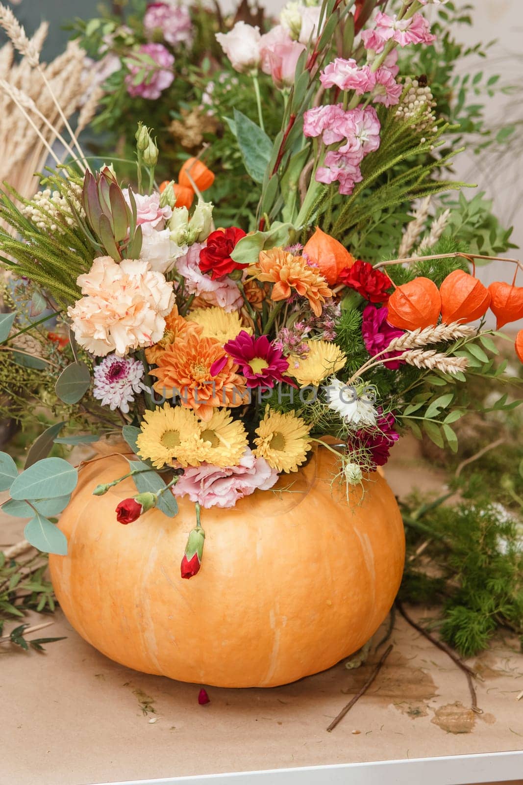 Flower arrangement in a pumpkin, autumn interior decor. Creating handmade autumn decor