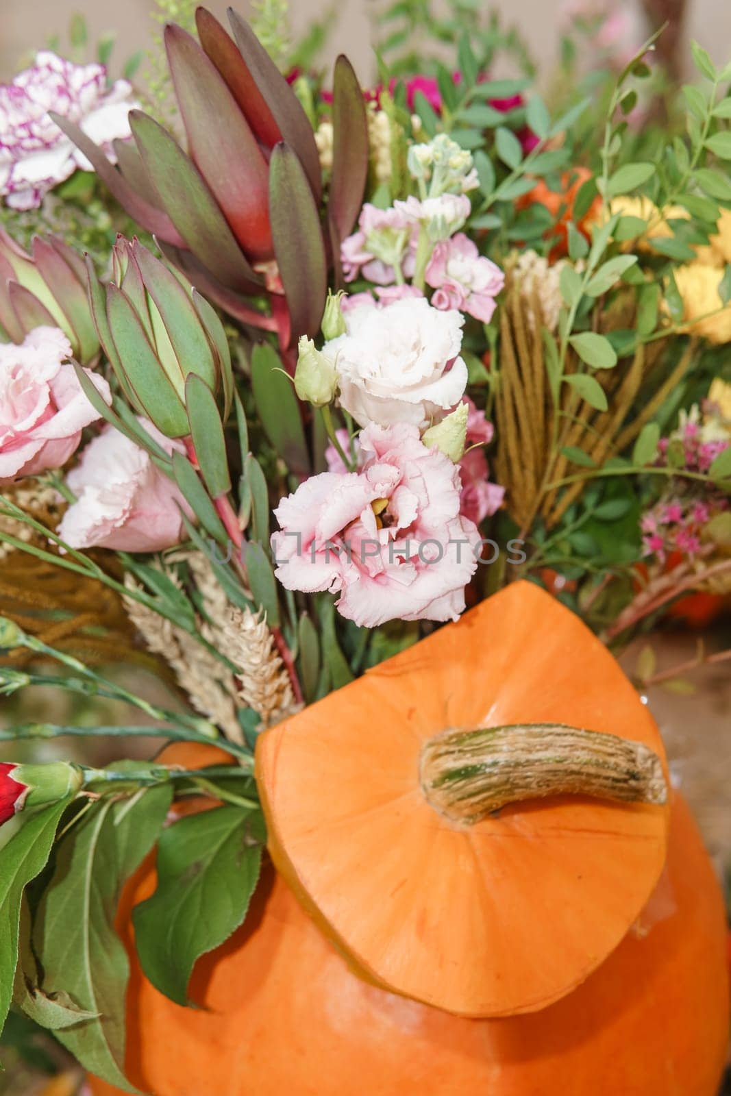 Flower arrangement in a pumpkin, autumn interior decor. Creating handmade autumn decor
