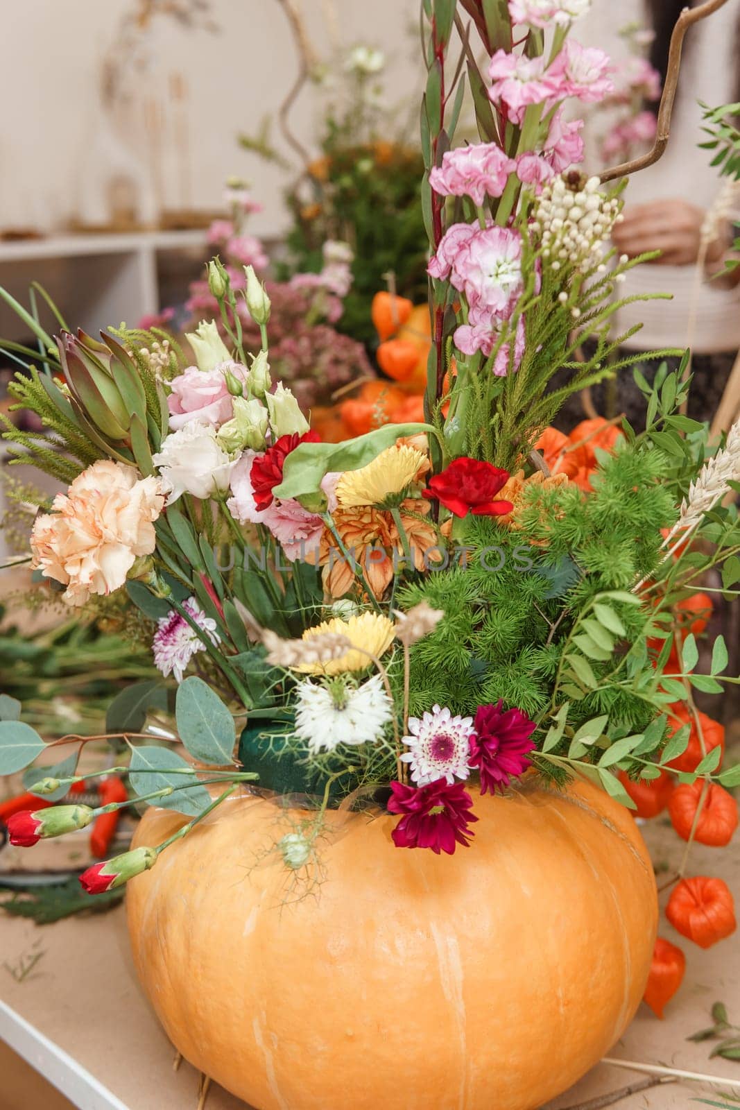 Flower arrangement in a pumpkin, autumn interior decor. Creating handmade autumn decor