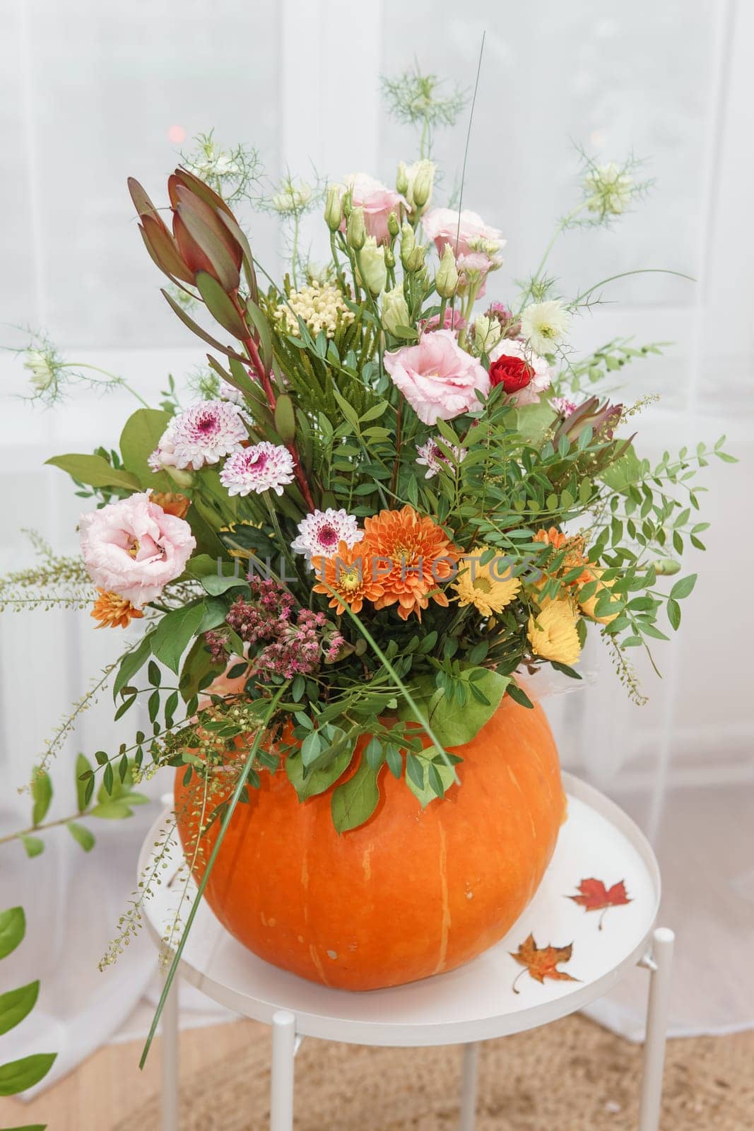 Flower arrangement in a pumpkin, autumn interior decor. Creating handmade autumn decor