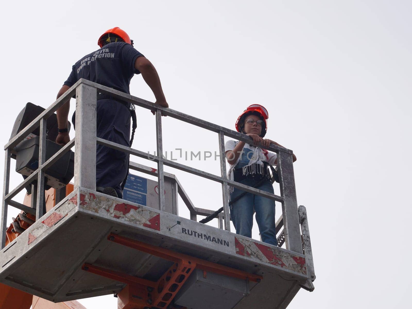 Varna, Bulgaria - September, 13, 2020: fireman and girl in safety helmets in a basket of a retractable fire boom, bottom view