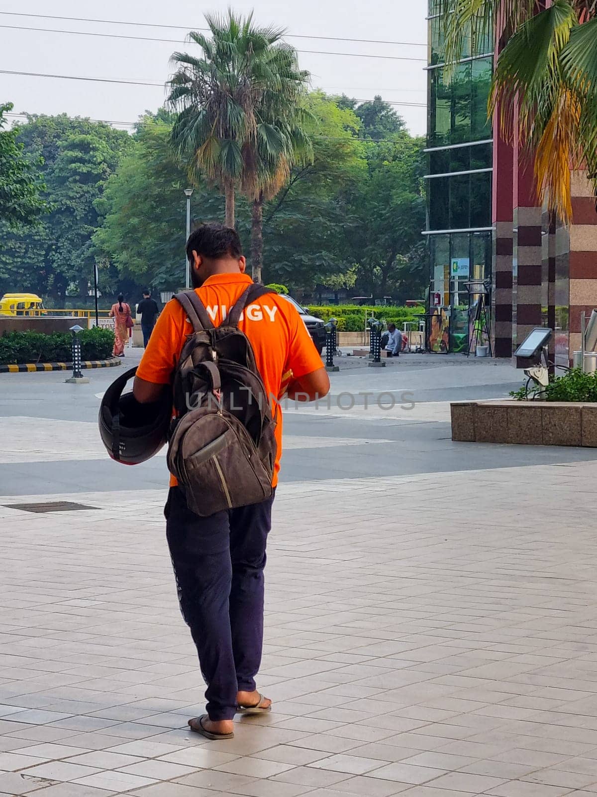 Delhi, India - 28th Oct 2023: Delivery boy rider from the food delivery app swiggy walking with a backpack searching for address
