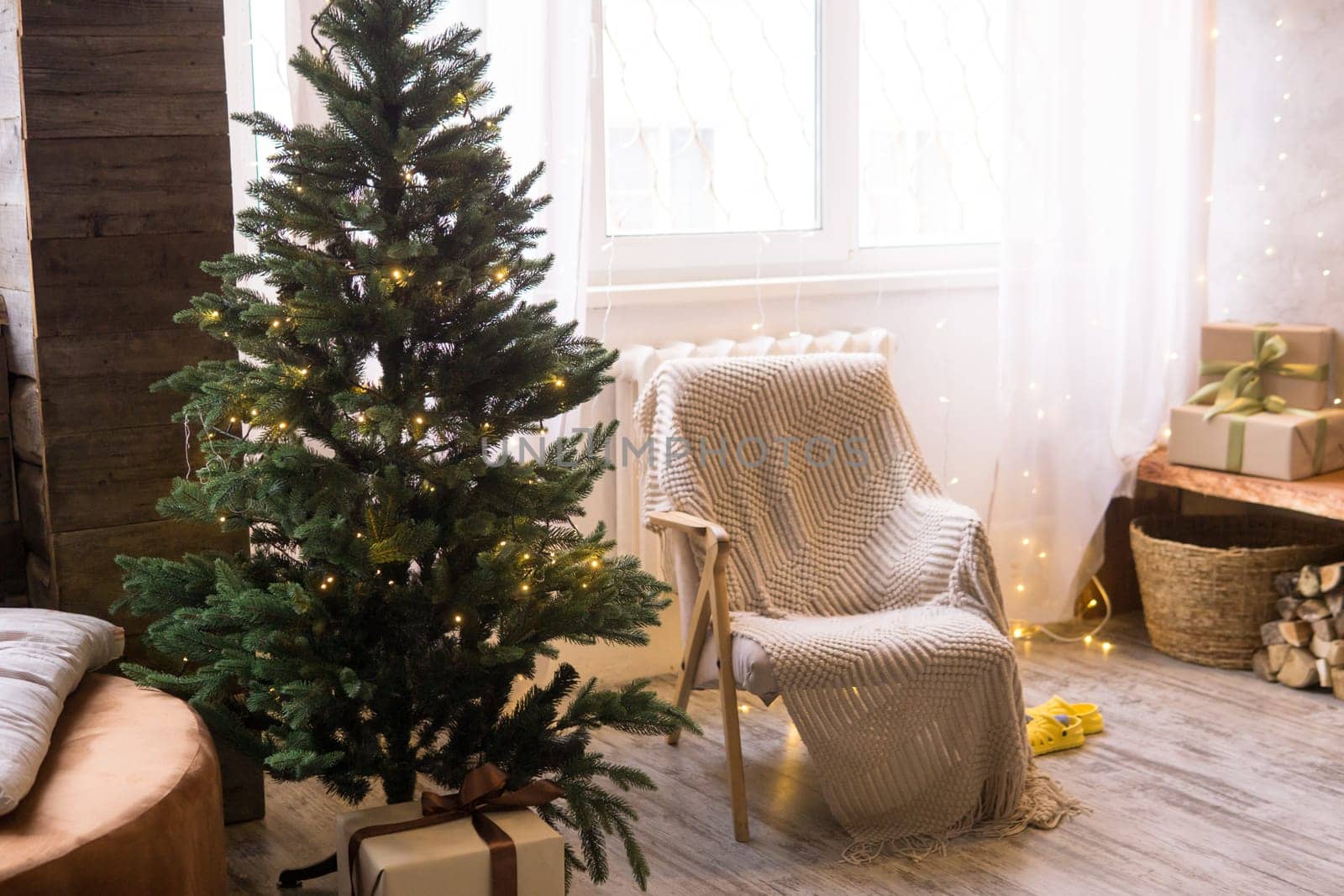 Home New Year's interior. Christmas tree with gifts, decorated with garlands. Cozy atmosphere of a home holiday, loft design of the room, Scandinavian style