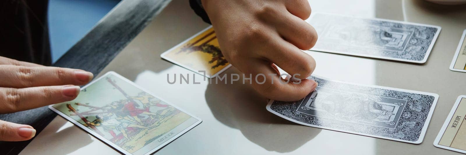 TVER, RUSSIA - FEBRUARY 11, 2023. Tarot cards, Tarot card divination, esoteric background. A woman makes a layout on the cards at the table. Divination, predictions on tarot cards