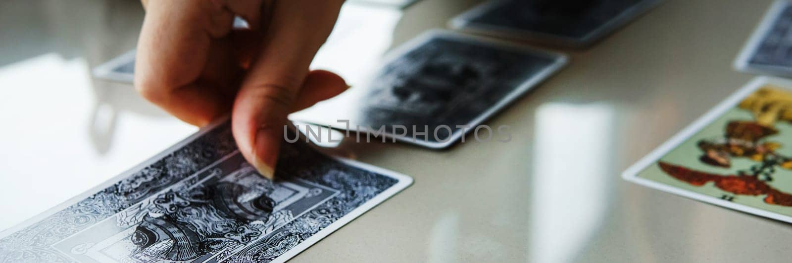 TVER, RUSSIA - FEBRUARY 11, 2023. Tarot cards, Tarot card divination, esoteric background. A woman makes a layout on the cards at the table. Divination, predictions on tarot cards