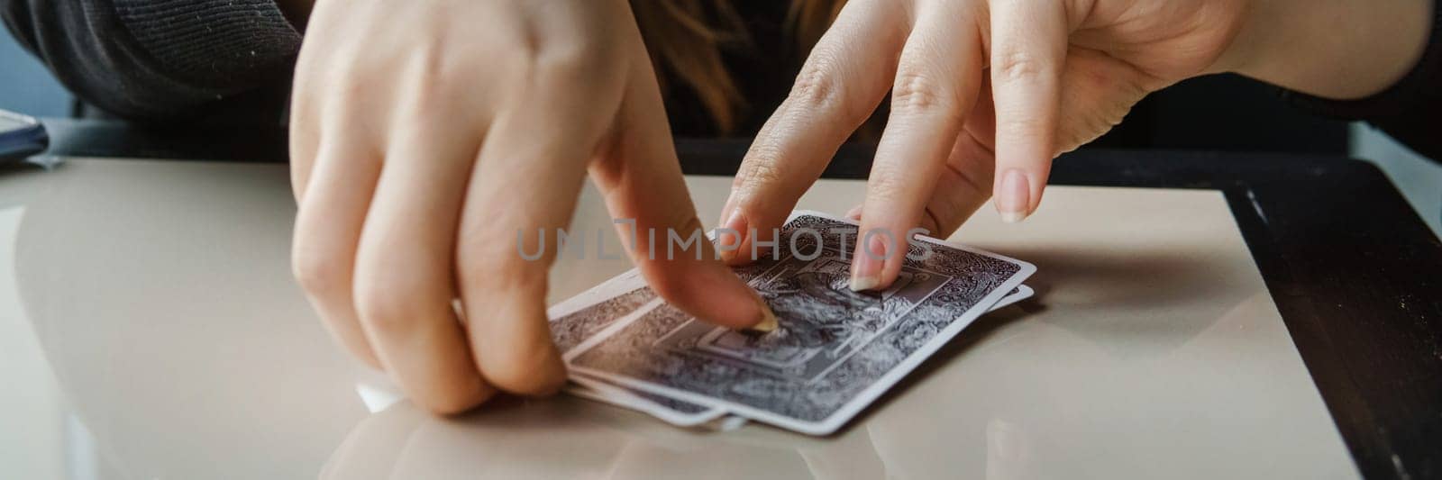 TVER, RUSSIA - FEBRUARY 11, 2023. Tarot cards, Tarot card divination, esoteric background. A woman makes a layout on the cards at the table. Divination, predictions on tarot cards