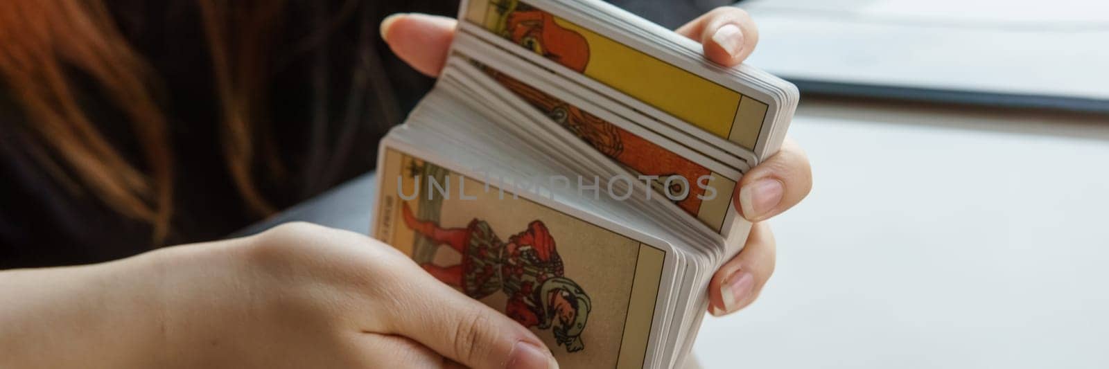 TVER, RUSSIA - FEBRUARY 11, 2023. Tarot cards, Tarot card divination, esoteric background. A woman makes a layout on the cards at the table. Divination, predictions on tarot cards