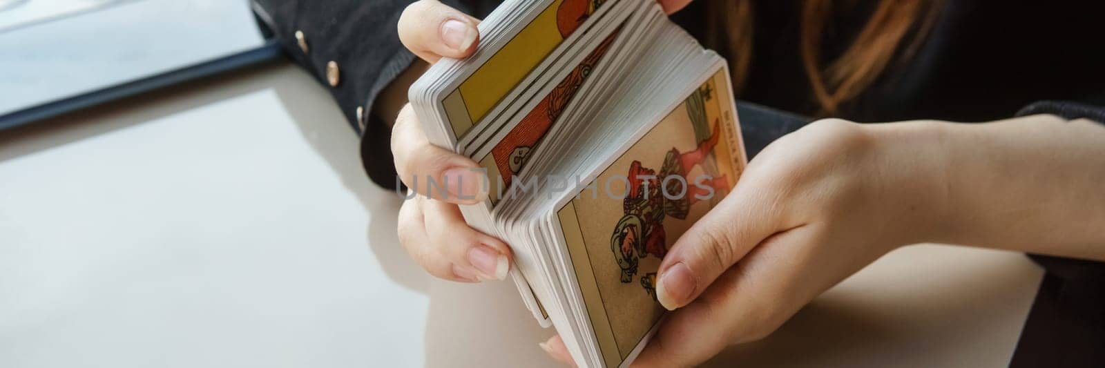 TVER, RUSSIA - FEBRUARY 11, 2023. Tarot cards, Tarot card divination, esoteric background. A woman makes a layout on the cards at the table. Divination, predictions on tarot cards