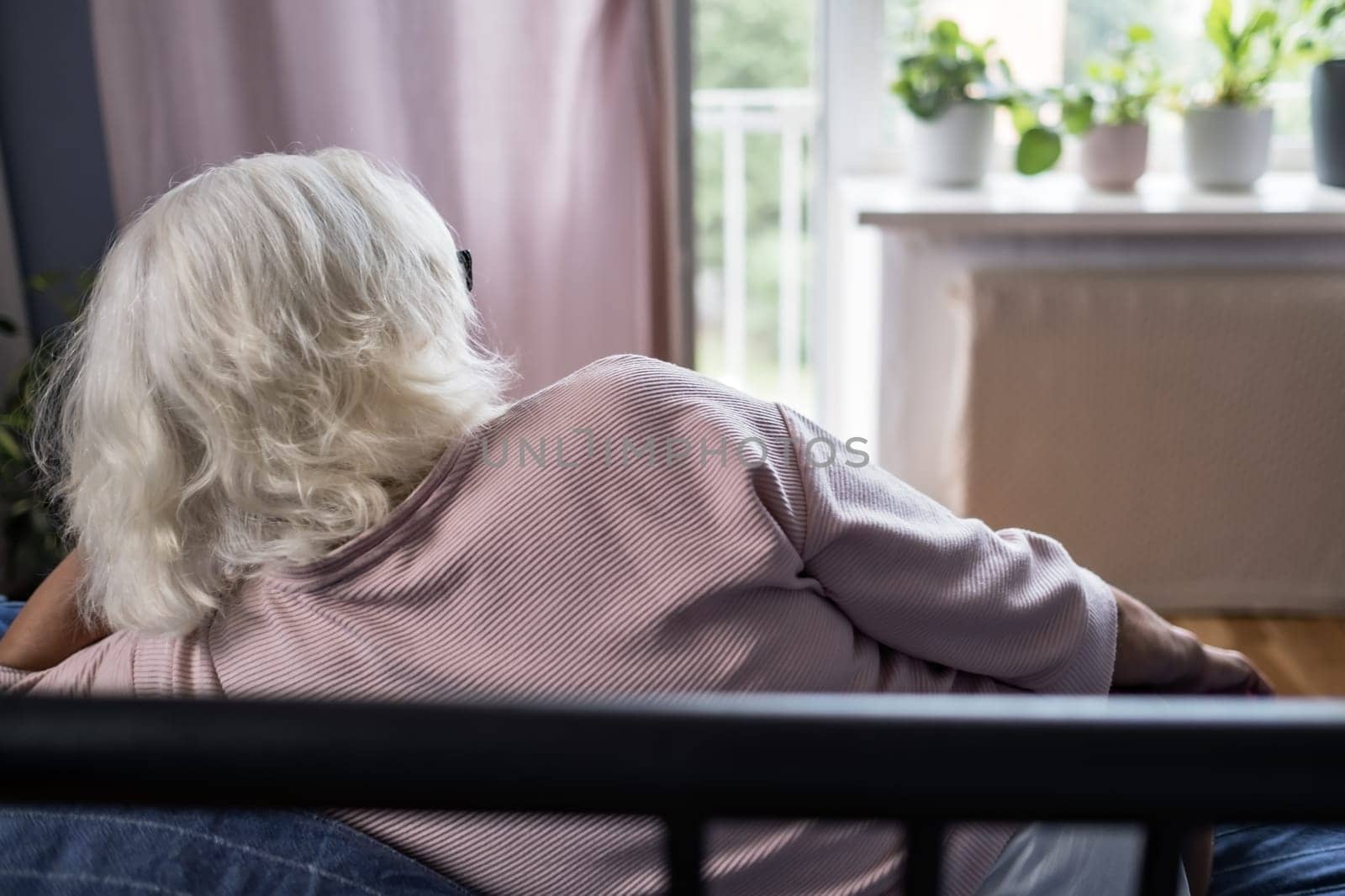 Resting smiling elderly woman reclining on a comfy sofa calm, meditating, sleeping, and enjoying a relaxing stress-free weekend at home. Peaceful calm grandma daydreams and meditates.