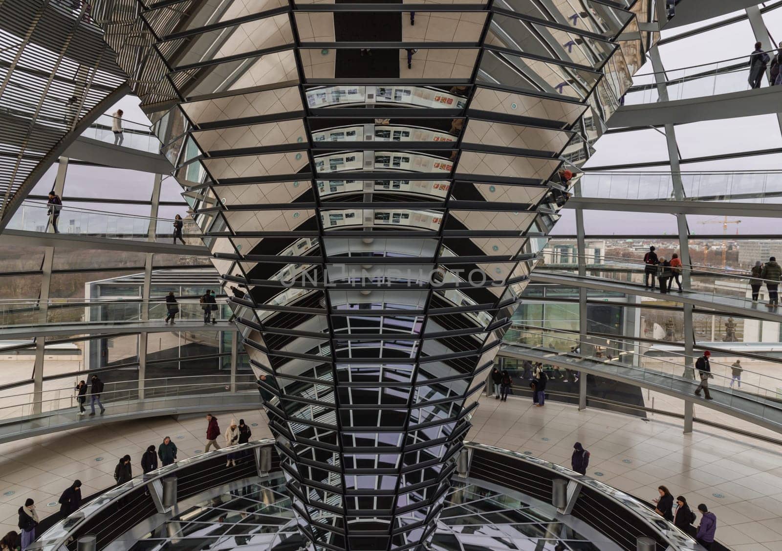 Berlin, Germany - Dec 20, 2023 - Several tourists visitor inside the futuristic glass dome of Reichstag building. Contemporary architecture of the Cupola of the Reichstag dome, a major tourist attraction of the berlin city, Copy space, Selective focus.