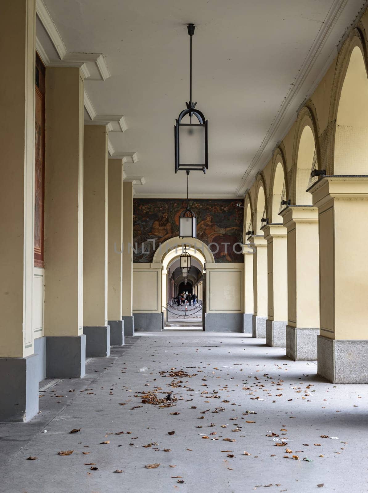 Munich, Germany - Dec 21, 2023 - Perspective view of Long corridor with Antique lantern hanging from ceiling and Beautiful columns inside Hofgartenarkaden (Munchen). Design elements of European architecture structure, Space for text, Selective focus.
