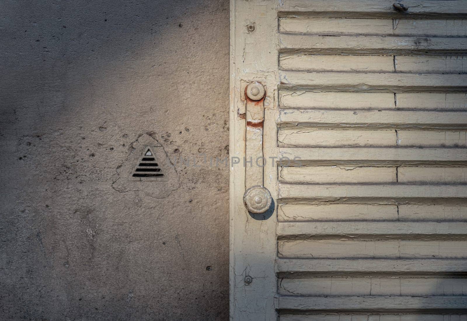 France, Paris - Jan 03, 2024 - The sun is shining through Vintage French Louvred Shutters and Knapen Siphons on wall (to vent damp air from inside the wall). Space for text, Selective focus.